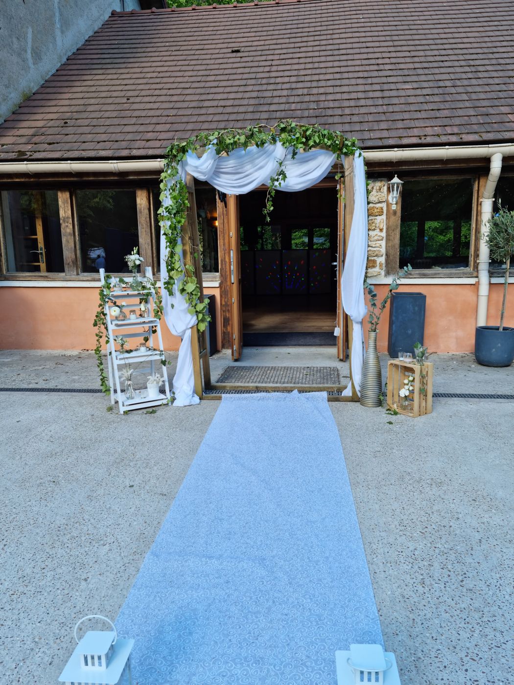 Entrée de la salle avec allée blanche et arche fleurie